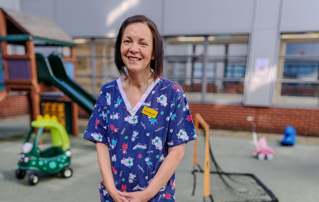 Female healthcare worker is standing in a courtyard surrounded by play equipment