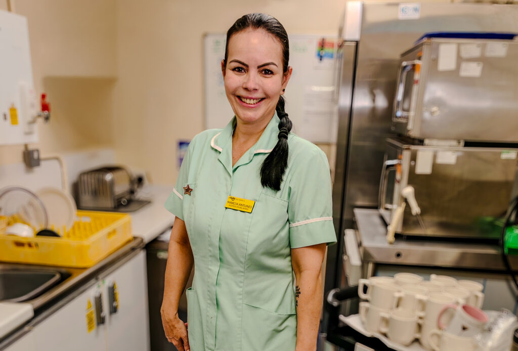 A female health worker is smiling straight into the camera wearing a green uniform