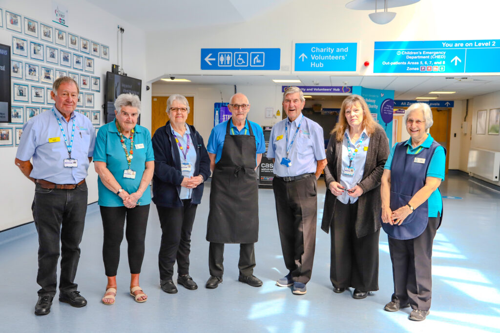 Female and male volunteers smiling into the camera in a hospital entrance